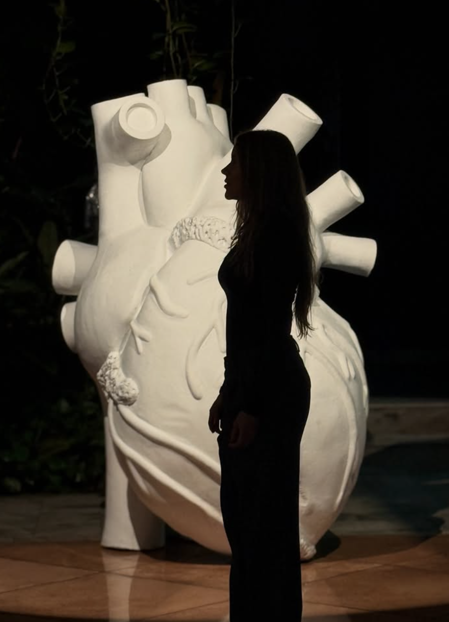 Una figura de perfil frente a una escultura monumental de un corazón blanco iluminado